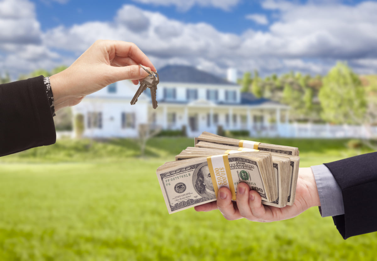 A contract, a small house, and house keys on a table