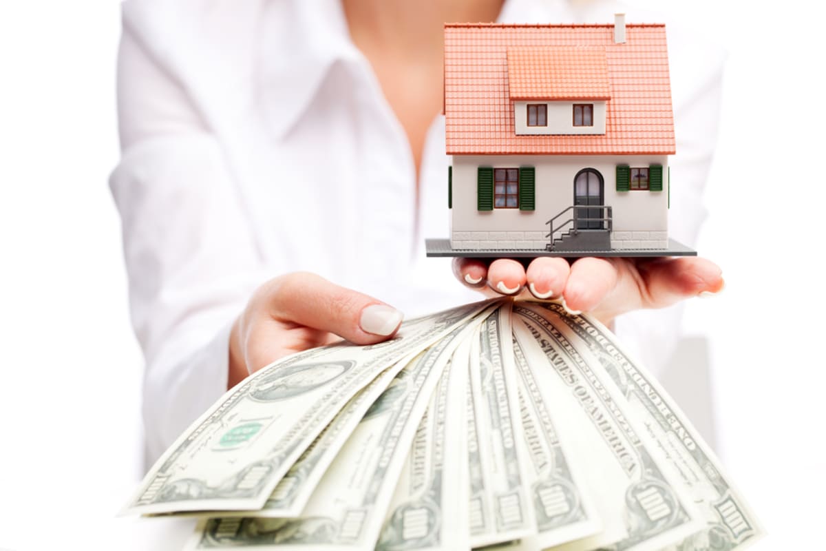 A woman holding cash and a model house, we buy houses cash Minneapolis concept