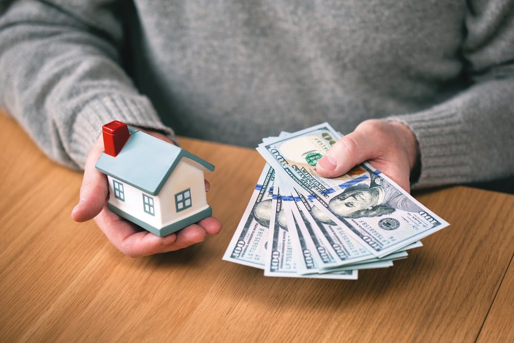 Holding cash next to a model house