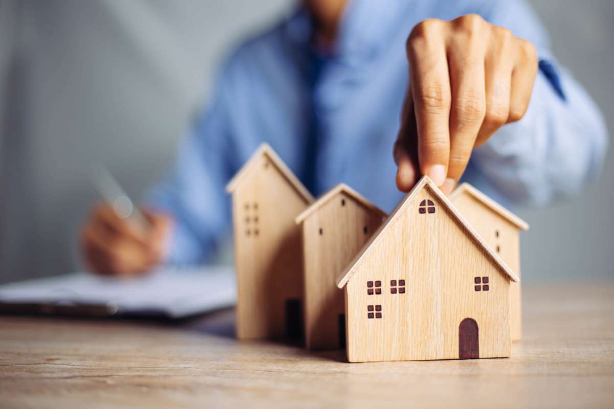 Man choosing mini wood house model, real estate agents concept. 