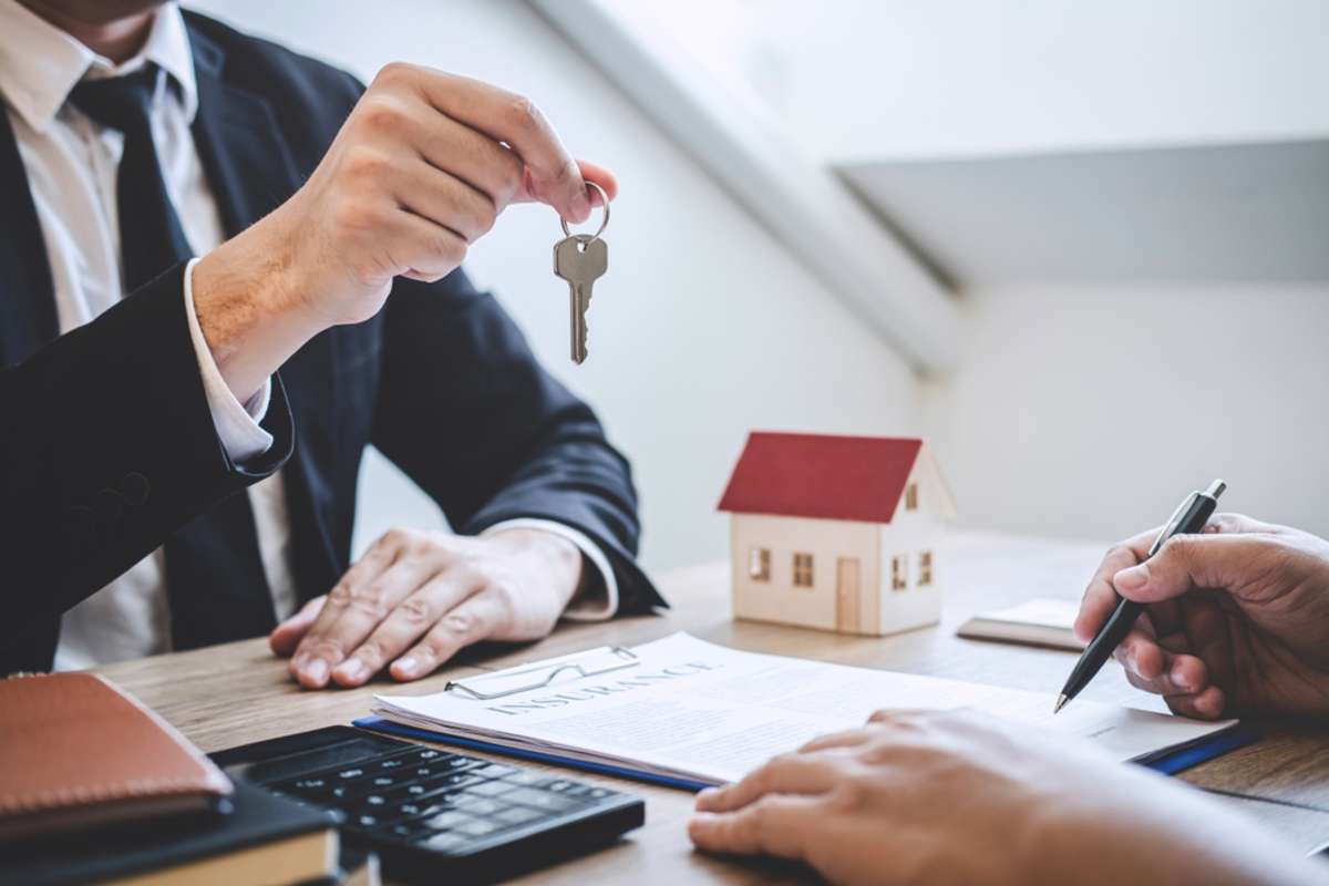 Estate agent giving house keys to client after signing agreement contract real estate with approved mortgage application form