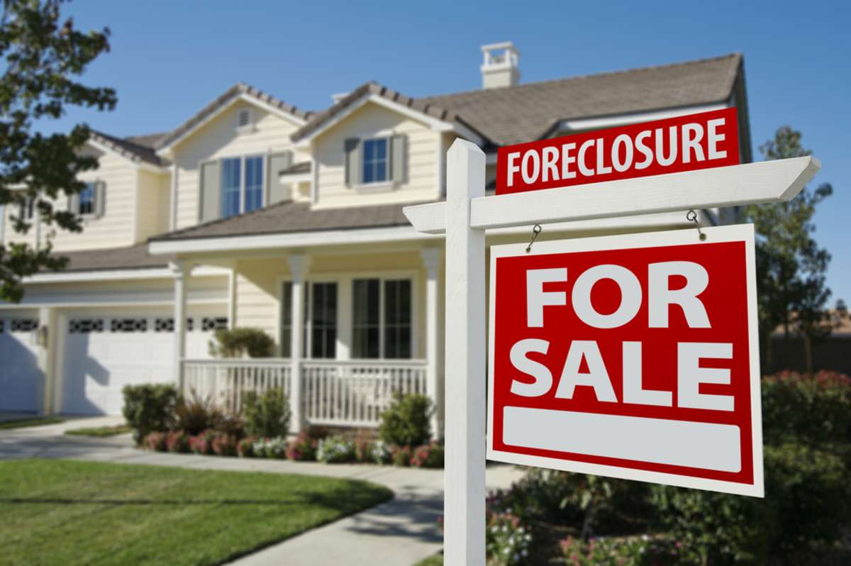 Foreclosure "For Sale" sign in front of a house, companies that buy homes for cash concept. 