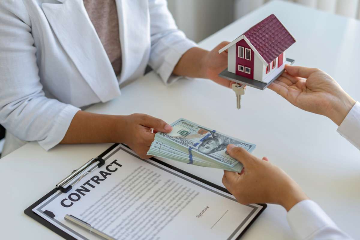 Hands exchanging cash for house key, cash for houses, MN, concept
