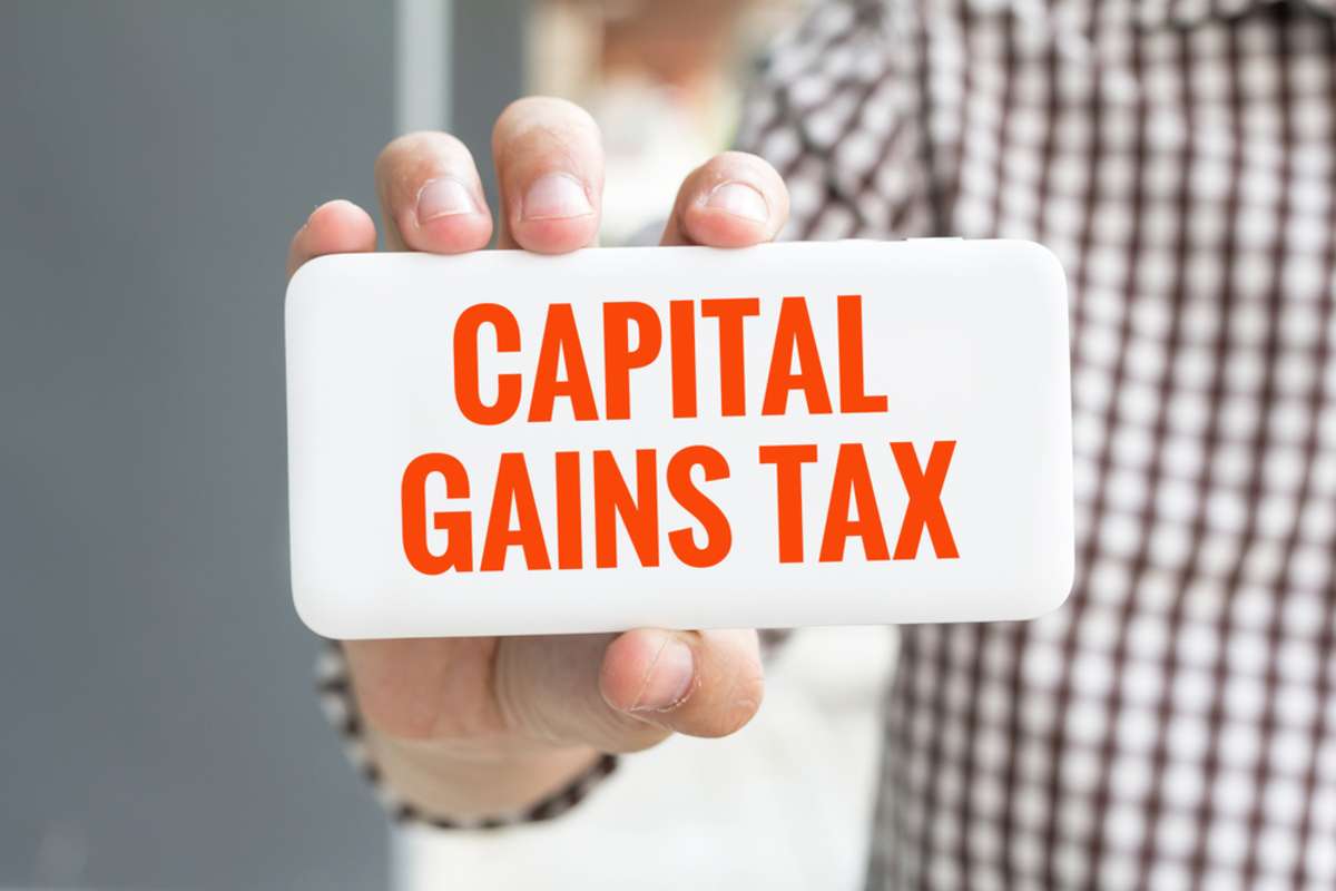 Man holding a sign saying capital gains tax, we buy houses, Minneapolis, concept