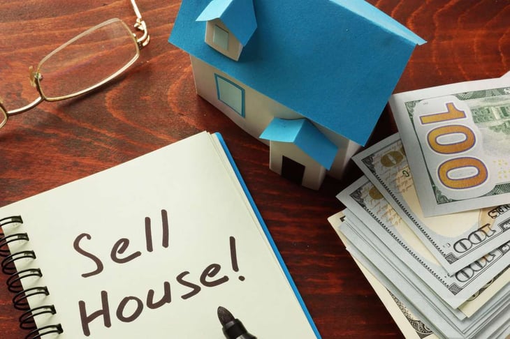 Notebook with the words Sell house on the table and money, sell house fast Twin Cities concept. 