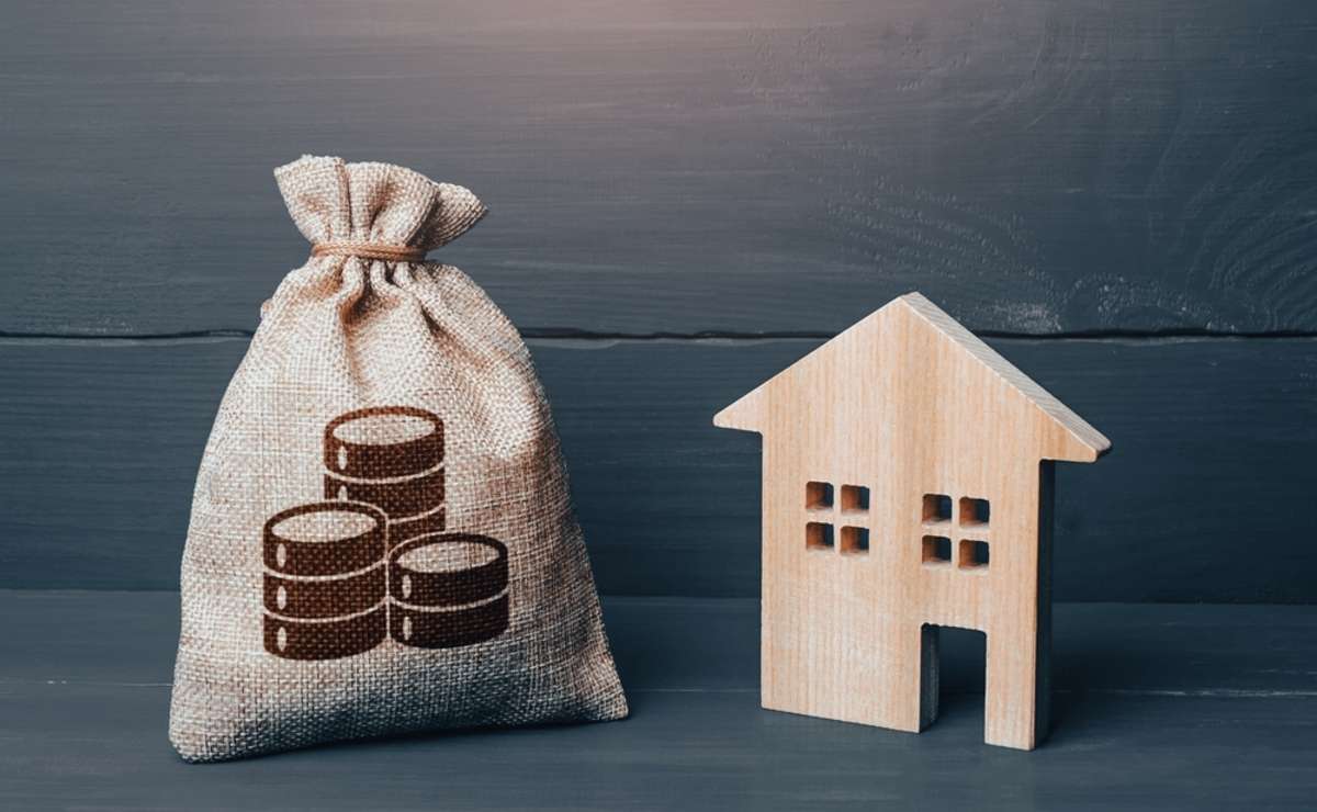 Wooden house and cash coins money bag