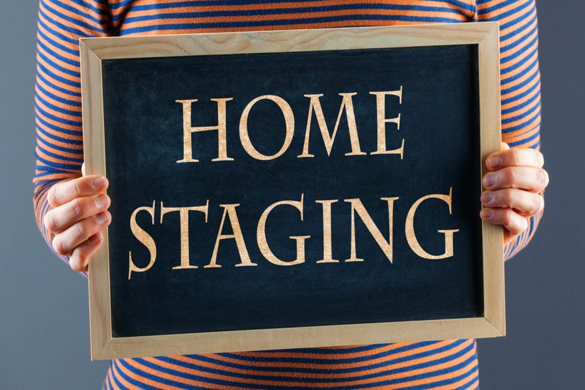 A woman holding a chalkboard with Home Staging on it, cash for houses concept