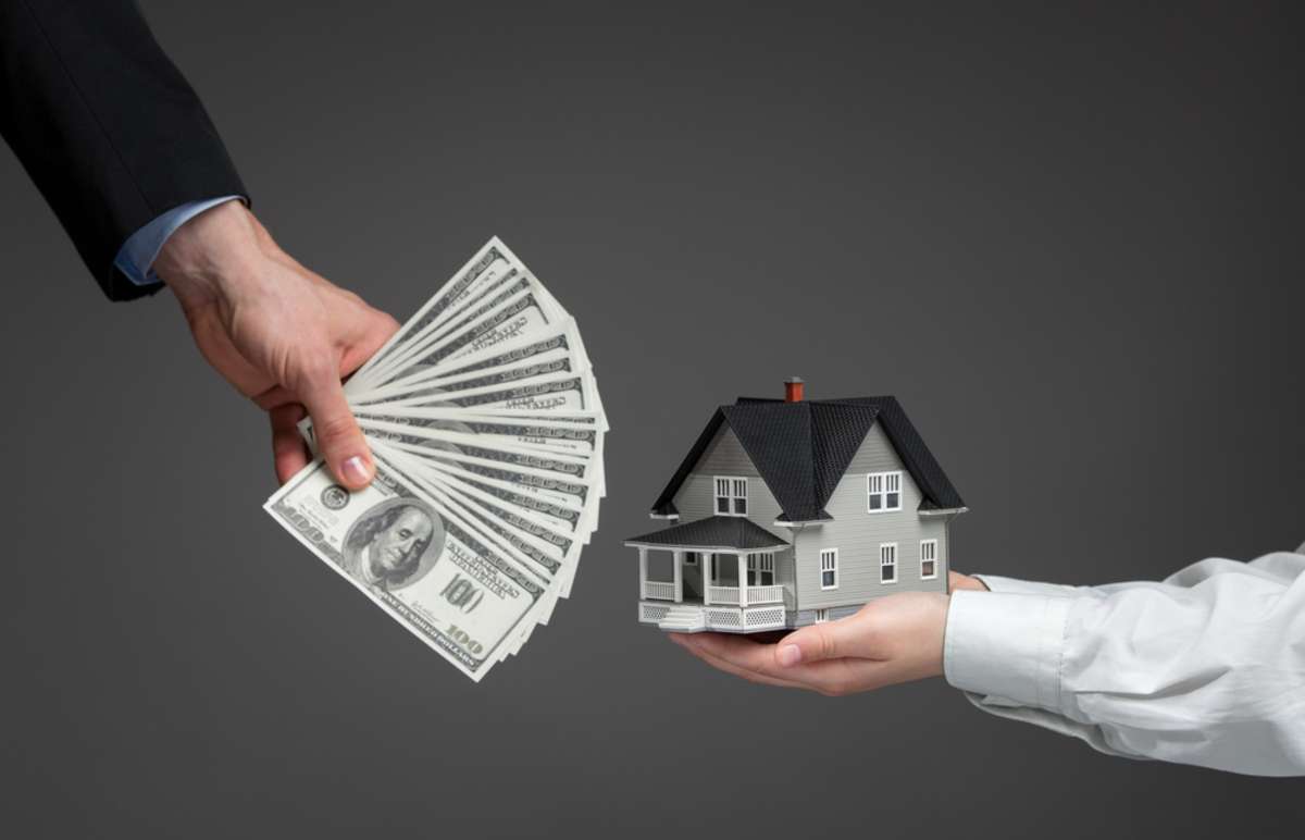 Hand with cash and a model home, we buy houses cash Minneapolis concept. 