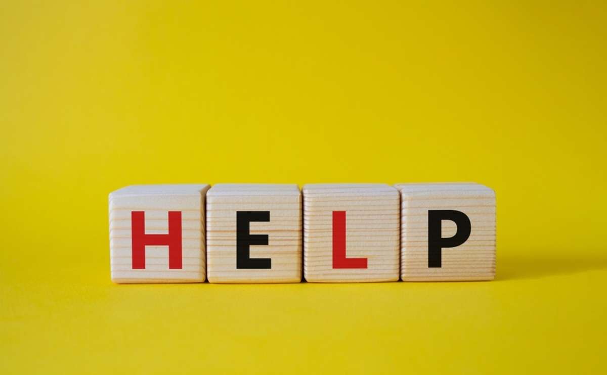 Help spelled in wooden blocks on a yellow background, a house cash offer is a help for financial stress concept